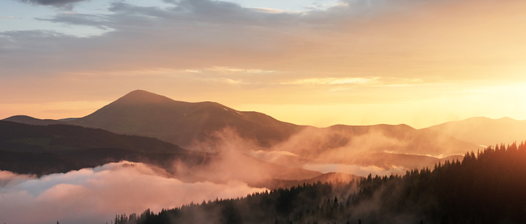 beautiful-sunset-mountains-landscape-with-sun-light-shining-through-orange-clouds-fog 1